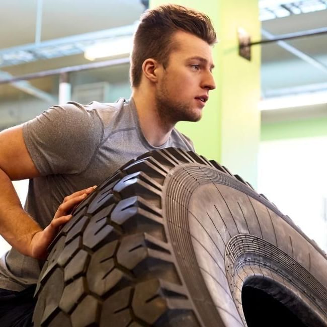 Man pushing tyre during strongman workout