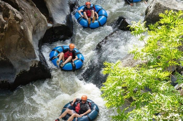 People enjoying the water tubing experience in the river near Hotel Rio Perdido