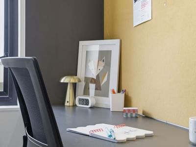 Office area with desk, chair, framed picture, and supplies at UniLodge Auckland City.