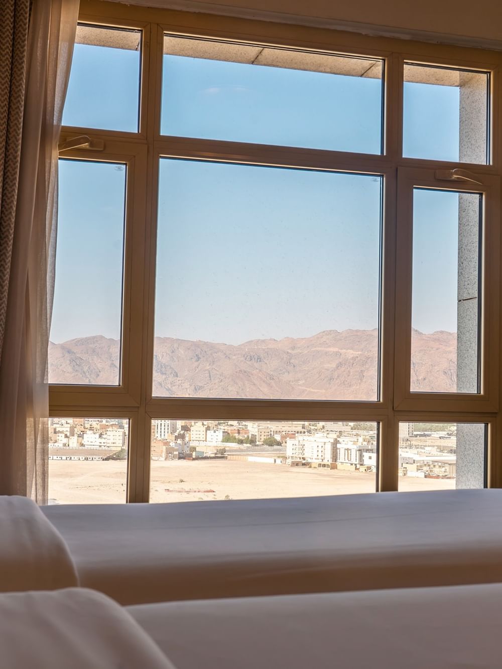منظر لسريرين منفصلين ومناظر الصحراء من خلال نافذة في فندق سجى ورويك المدينة المنورة.