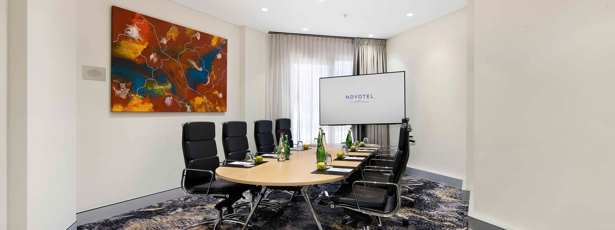 Boardroom set-up facing the projector screen in The Riverina Boardroom at Novotel Sydney on Darling Harbour