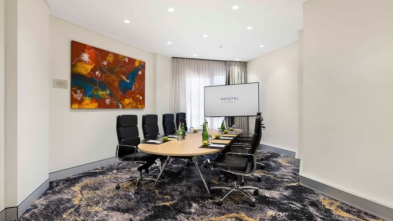 Boardroom set-up facing the projector screen in The Riverina Boardroom at Novotel Sydney on Darling Harbour