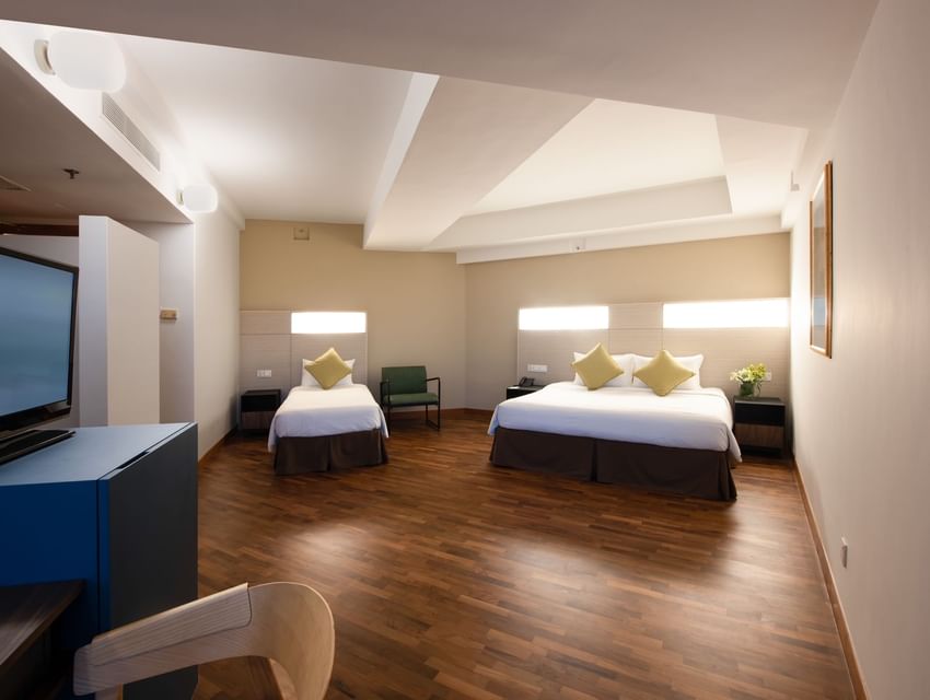 TV and workspace by the plush beds in the Family King Room with polished hardwood floors at YWCA Fort Canning