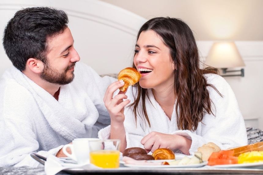 Couple enjoying breakfast in bed at MCM Elegante Suites