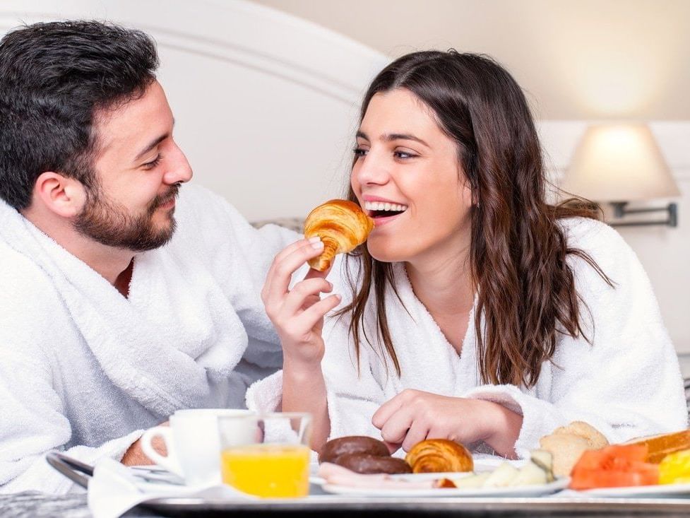 Couple enjoying breakfast in bed at MCM Elegante Suites