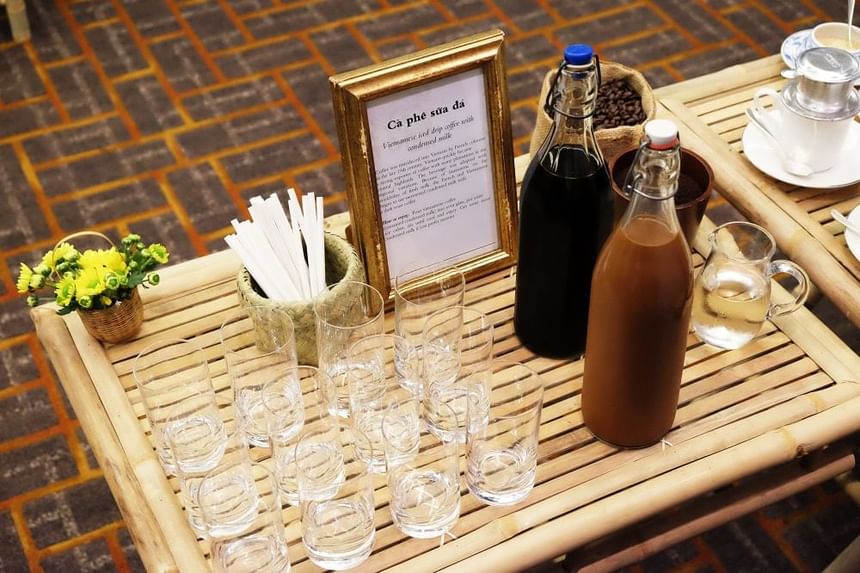 Bamboo table displaying glasses, bottles of Vietnamese coffee, a flower pot at Park Hyatt Saigon