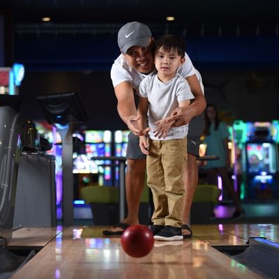 Father teaching his young son how to bowl in Paradise Pier at Margaritaville Resort Biloxi
