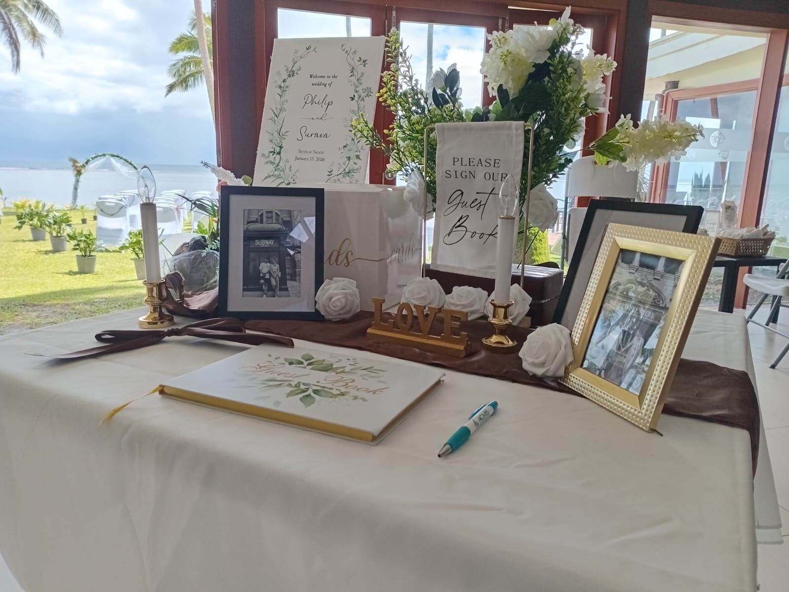 Decorated table with floral arrangements, wedding book, and guest book at Tambua Sands Beach Resort - [Redesign]