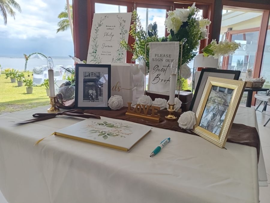 Decorated table with floral arrangements, wedding book, and guest book at Tambua Sands Beach Resort - [Redesign]