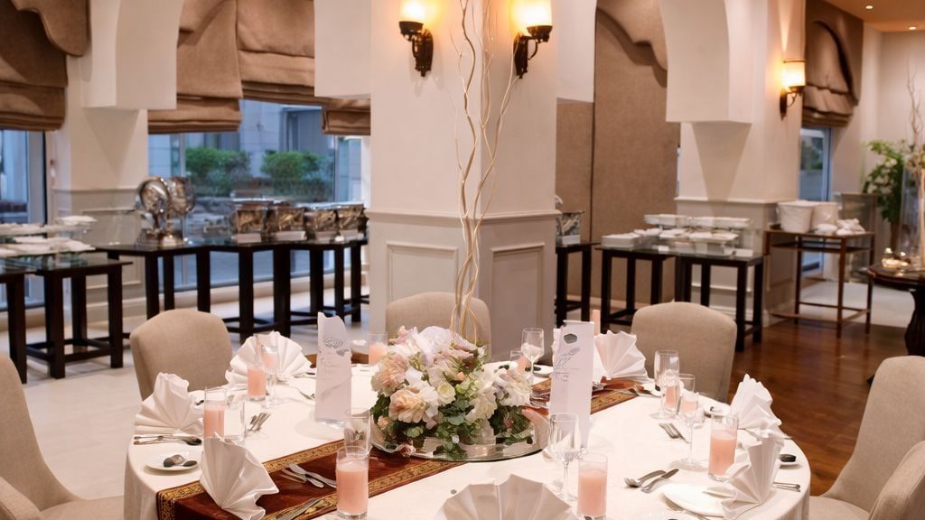 Elegant round dining table with floral centerpiece and pink beverages in Nazara hall at Serena Hotels & Resorts