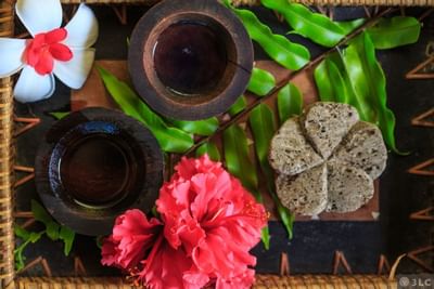 Spa setup with flowers, green leaves, and wooden bowls on a woven mat at Musket Cove Island Resort & Marina