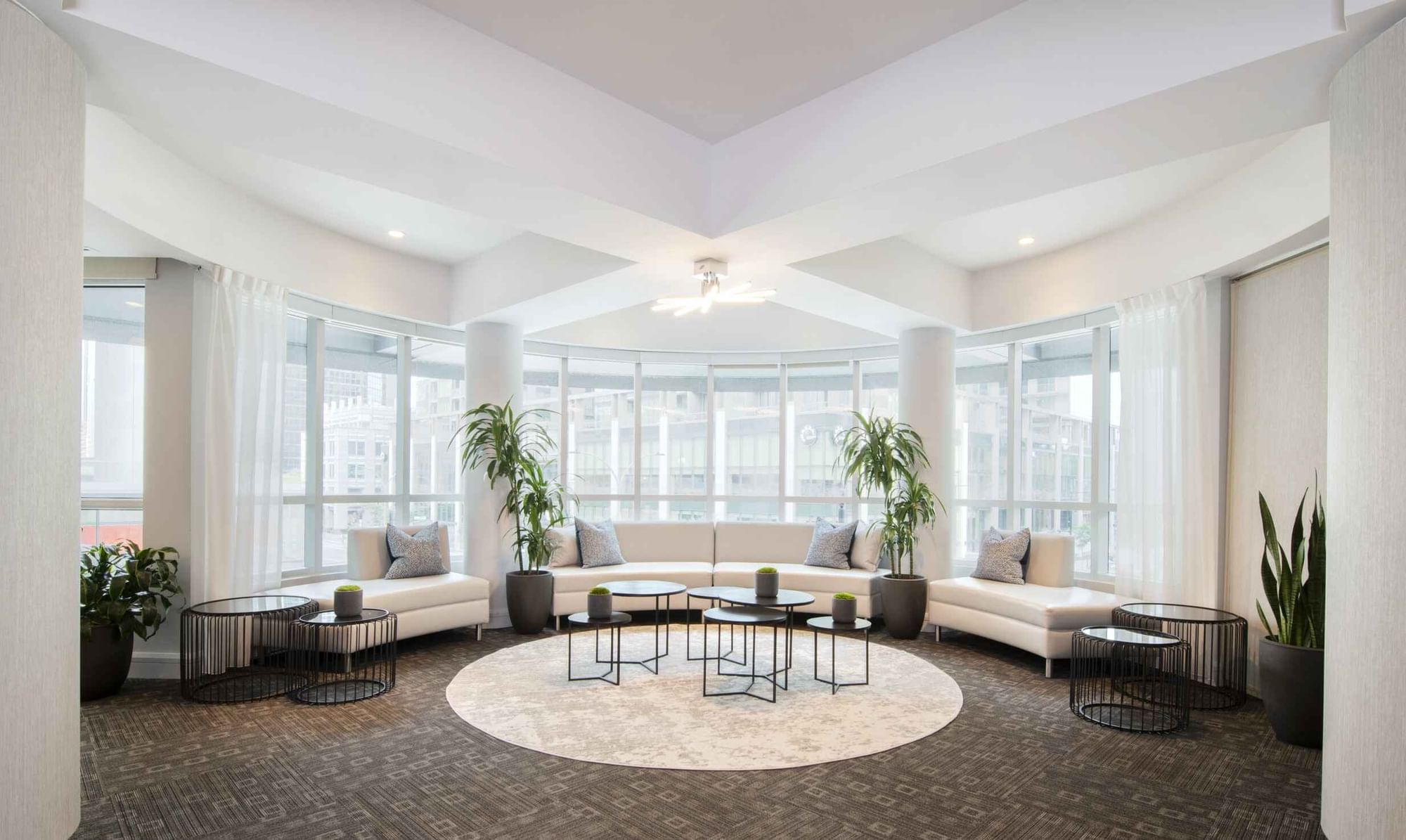 Salon De La Montagne lounge with white sofas and large windows overlooking the city skyline at Warwick Hotels and Resorts