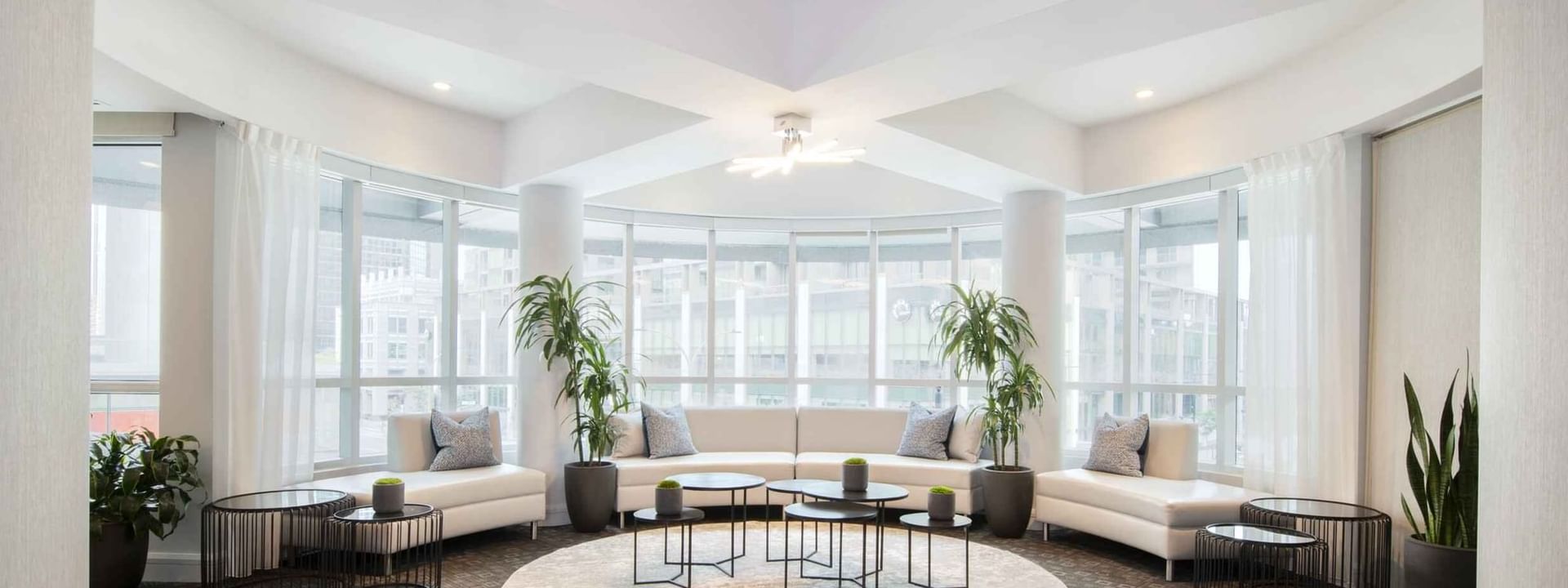 Salon De La Montagne lounge with white sofas and large windows overlooking the city skyline at Warwick Le Crystal Montreal