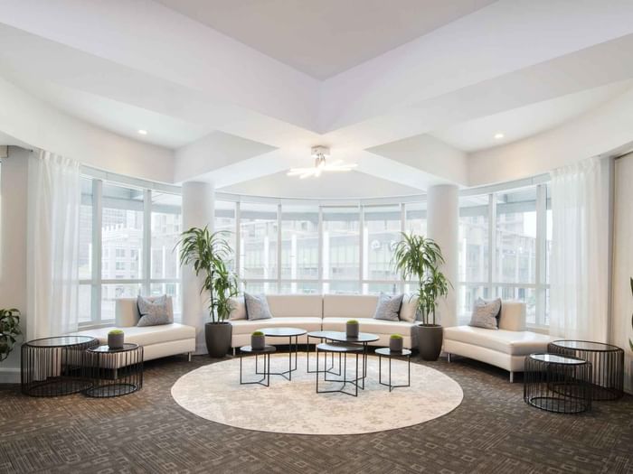 Salon De La Montagne lounge with white sofas and large windows overlooking the city skyline at Warwick Le Crystal Montreal