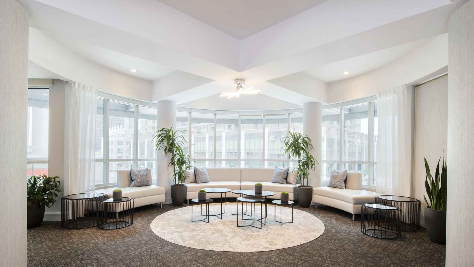 Salon De La Montagne lounge with white sofas and large windows overlooking the city skyline at Warwick Hotels and Resorts