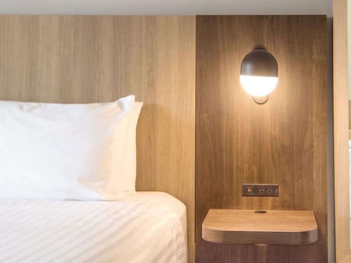 Modern king suite with wood-paneled wall, floating nightstand and view of soaker tub.