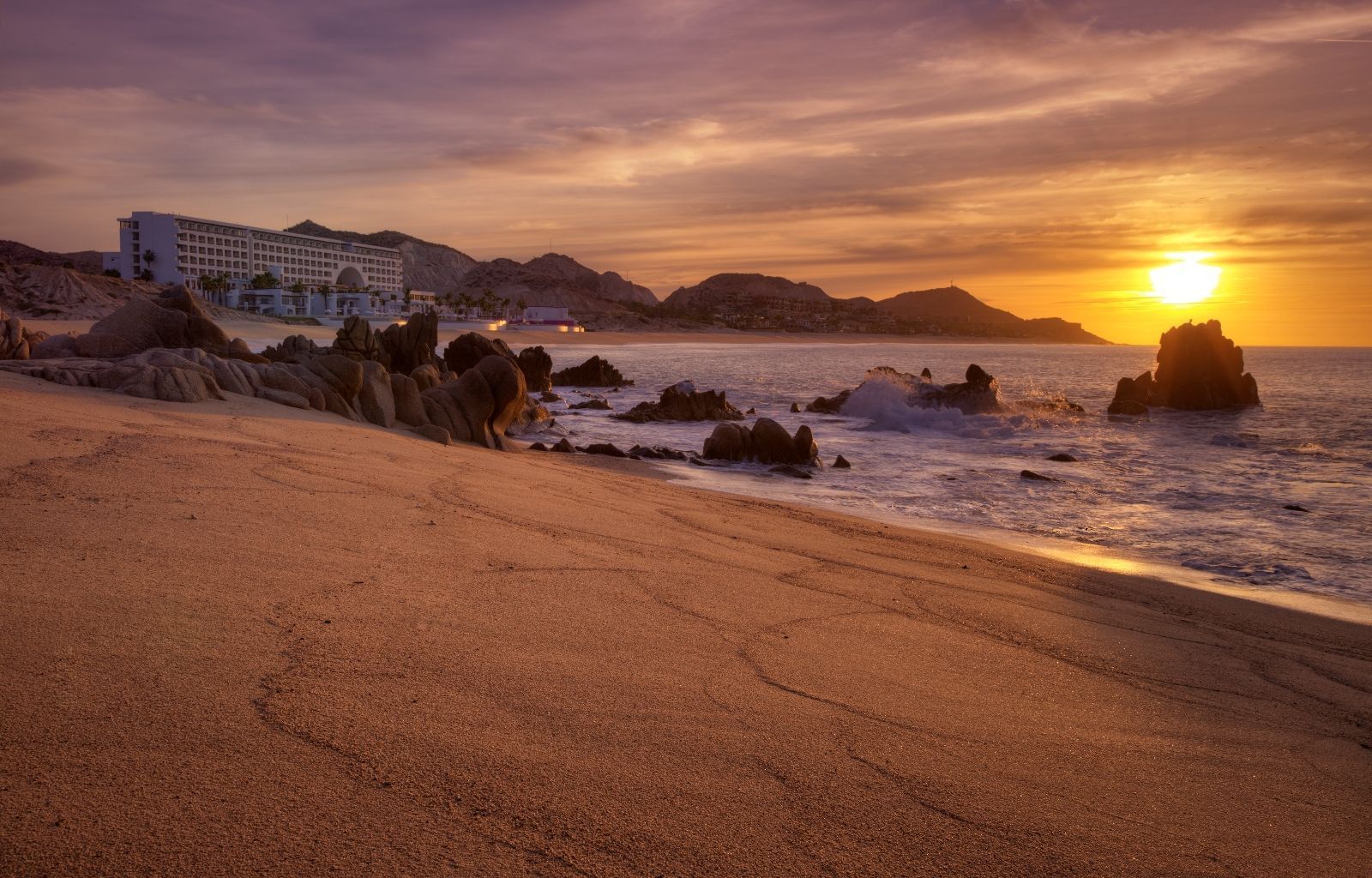 Rocks in an ocean by a sandy beach near Marquis Los Cabos