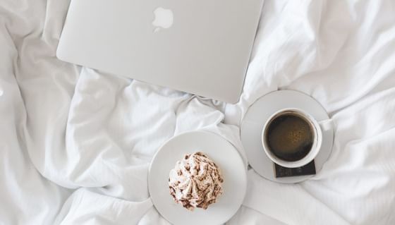 A laptop and a cup of coffee on a bed at Vasa Hotel Surabaya