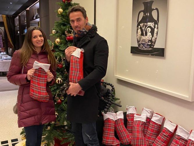 A couple holding their Christmas gifts at EMME Restaurant