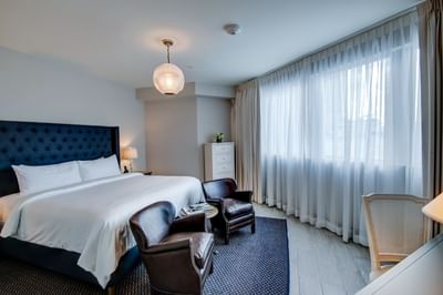 room with king bed, sitting area and tall dresser