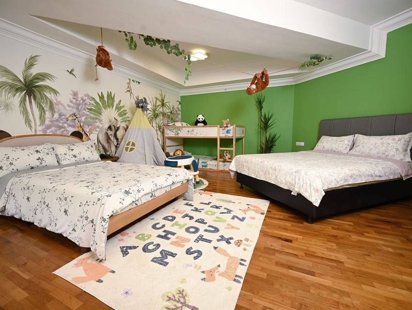 Jungle mural and a play teepee by the beds in Kids and Family Room with wooden floors and a letter rug at YWCA Fort Canning