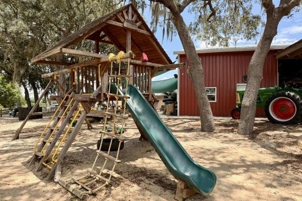 An outdoor playground structure with a slide and climbing ropes.