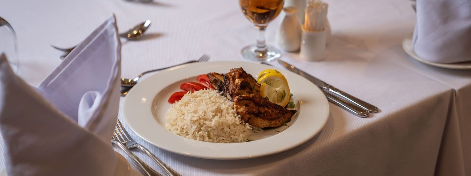 Grilled chicken breast served with white rice & tomato slices on white plate in AI Firdous restaurant at Saja Warwick Madinah