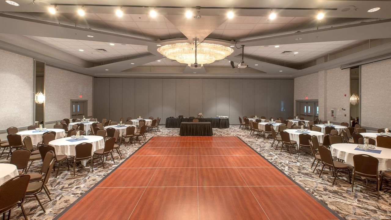 Large banquet hall with wooden dance floor and round tables.