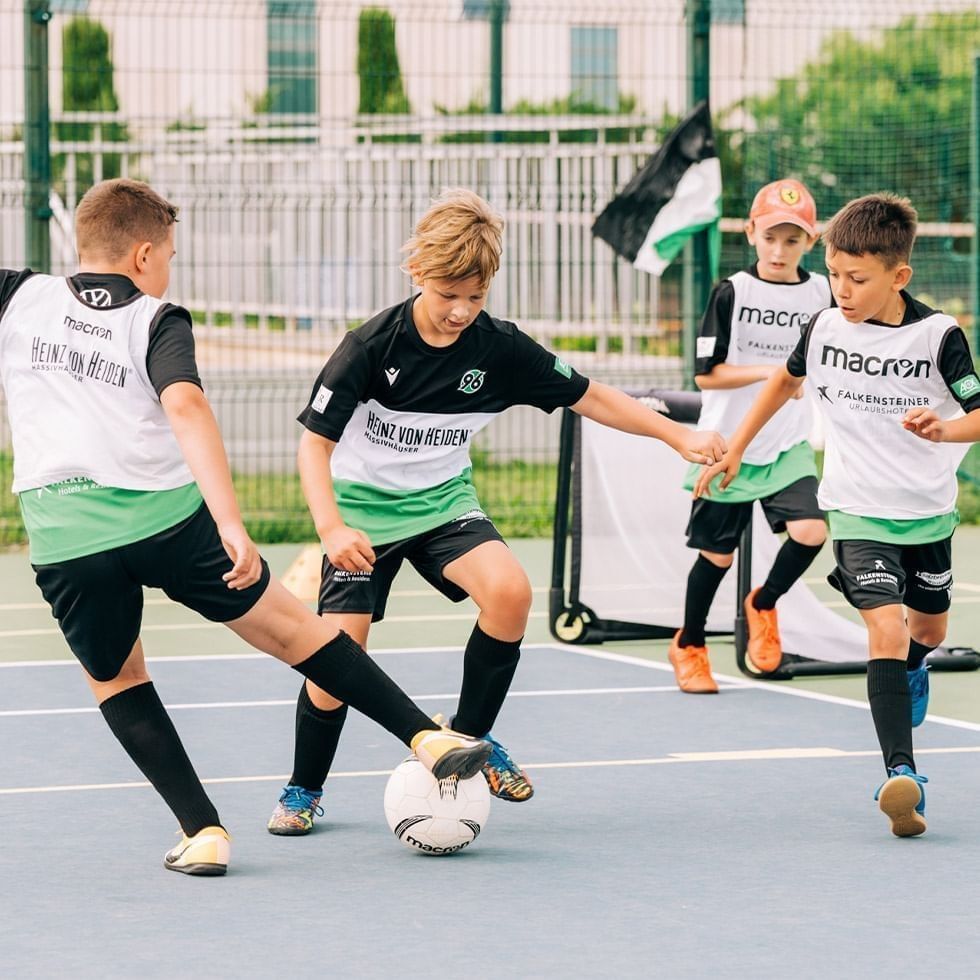 Bambini che giocano a calcio in un campo da calcio durante il HANNOVER 96 FOOTBALL CAMP.