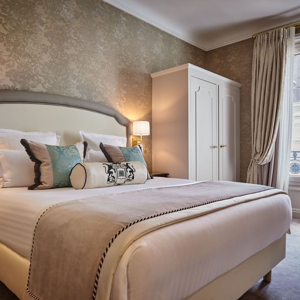Élégante chambre Deluxe avec un grand lit, du papier peint à motifs et une vue sur Paris à l'Hôtel Westminster - Paris.