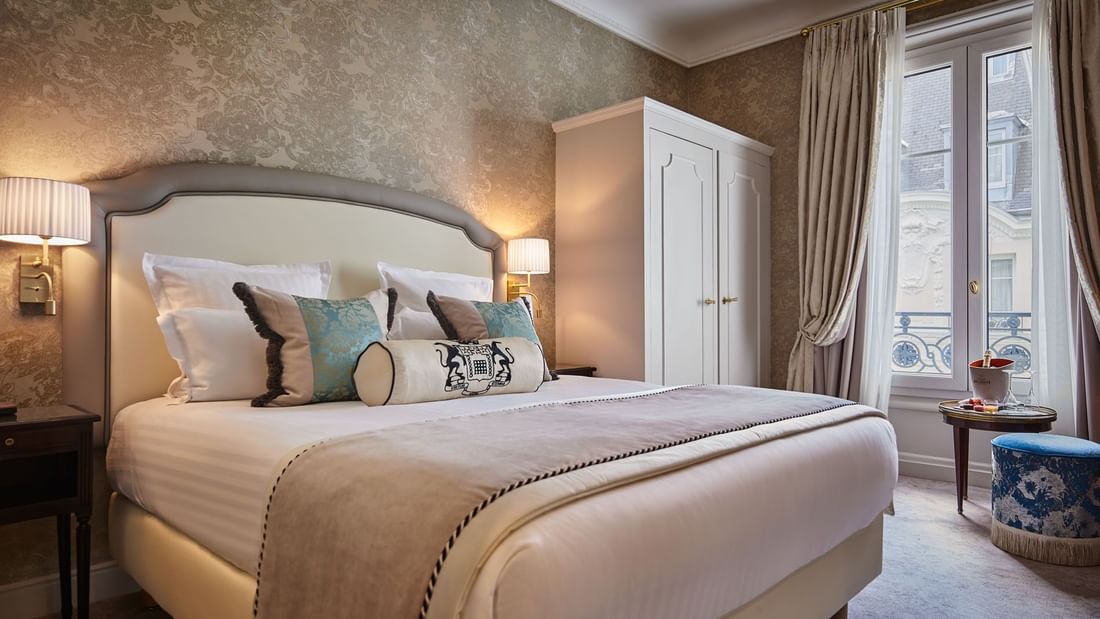 Élégante chambre Deluxe avec un grand lit, du papier peint à motifs et une vue sur Paris à l'Hôtel Westminster - Paris.