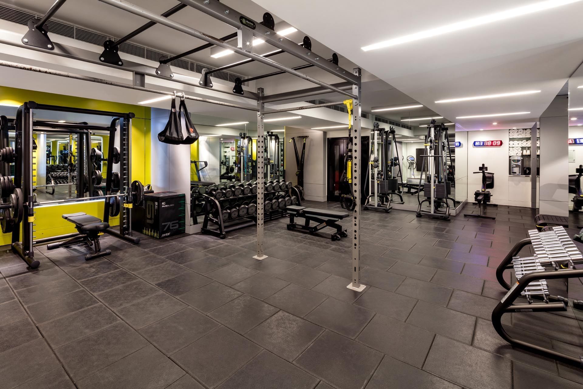 Well-equipped gym with various weights, machines, and workout areas at The May Fair Hotel