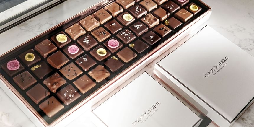 Box of assorted chocolates with elegant designs resting on a marble surface in Chocolaterie at Park Hyatt Saigon