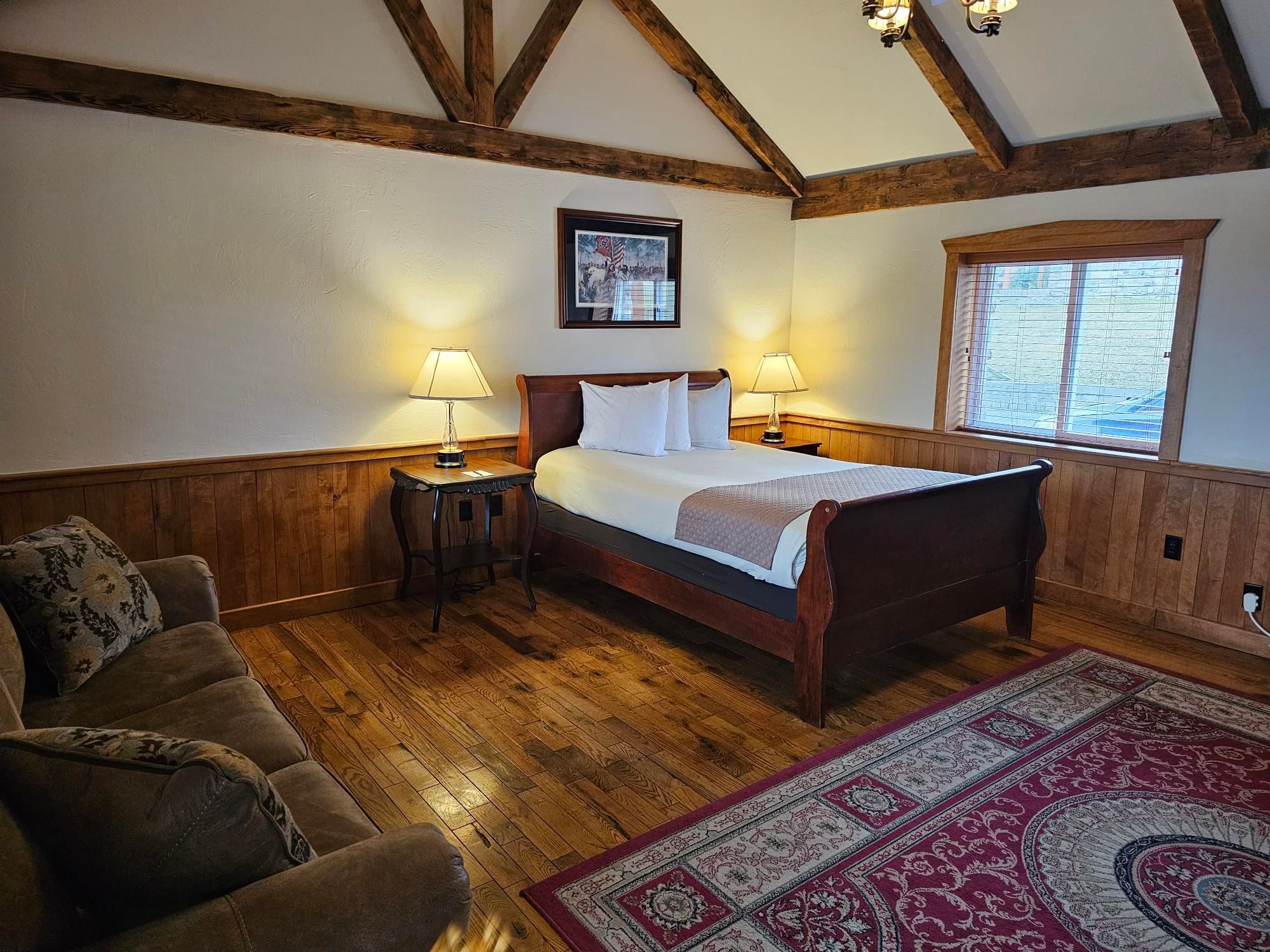 Cozy Presidental Lodge with wooden floors, bed, nightstands with lamps at The Lodges at Gettysburg, PA.