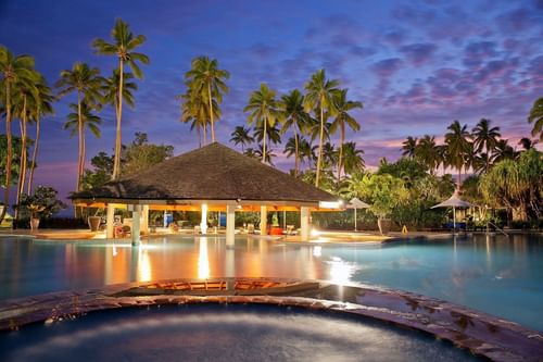 A pool with a gazebo and palm trees at The Naviti Resort - Fiji