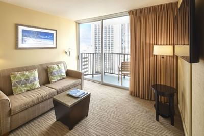 Living space with a cozy sofa & a TV by the balcony view in Superior Studio at Waikiki Resort Hotel by Sono