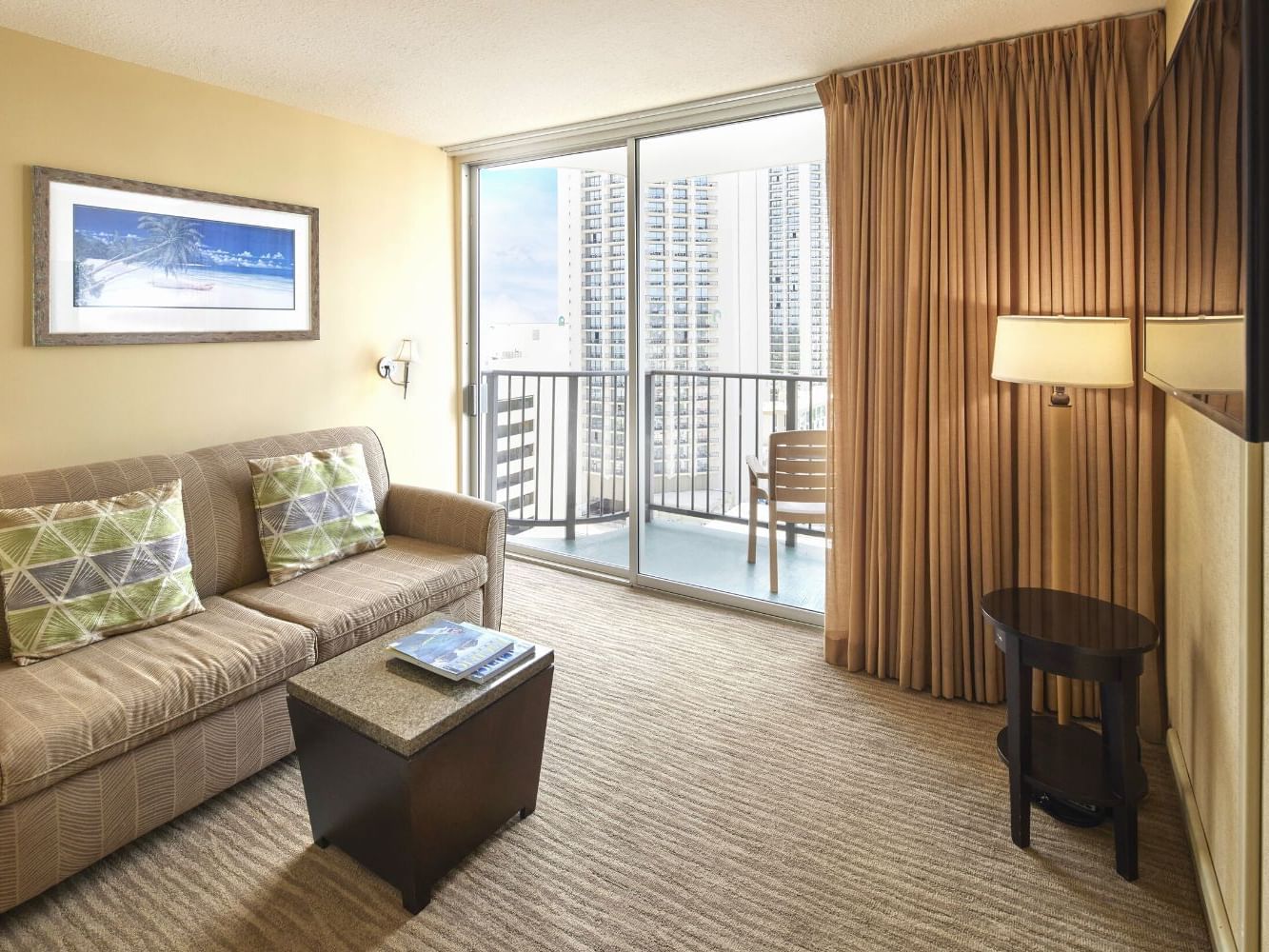 Living space with a cozy sofa & a TV by the balcony view in Superior Studio at Waikiki Resort Hotel