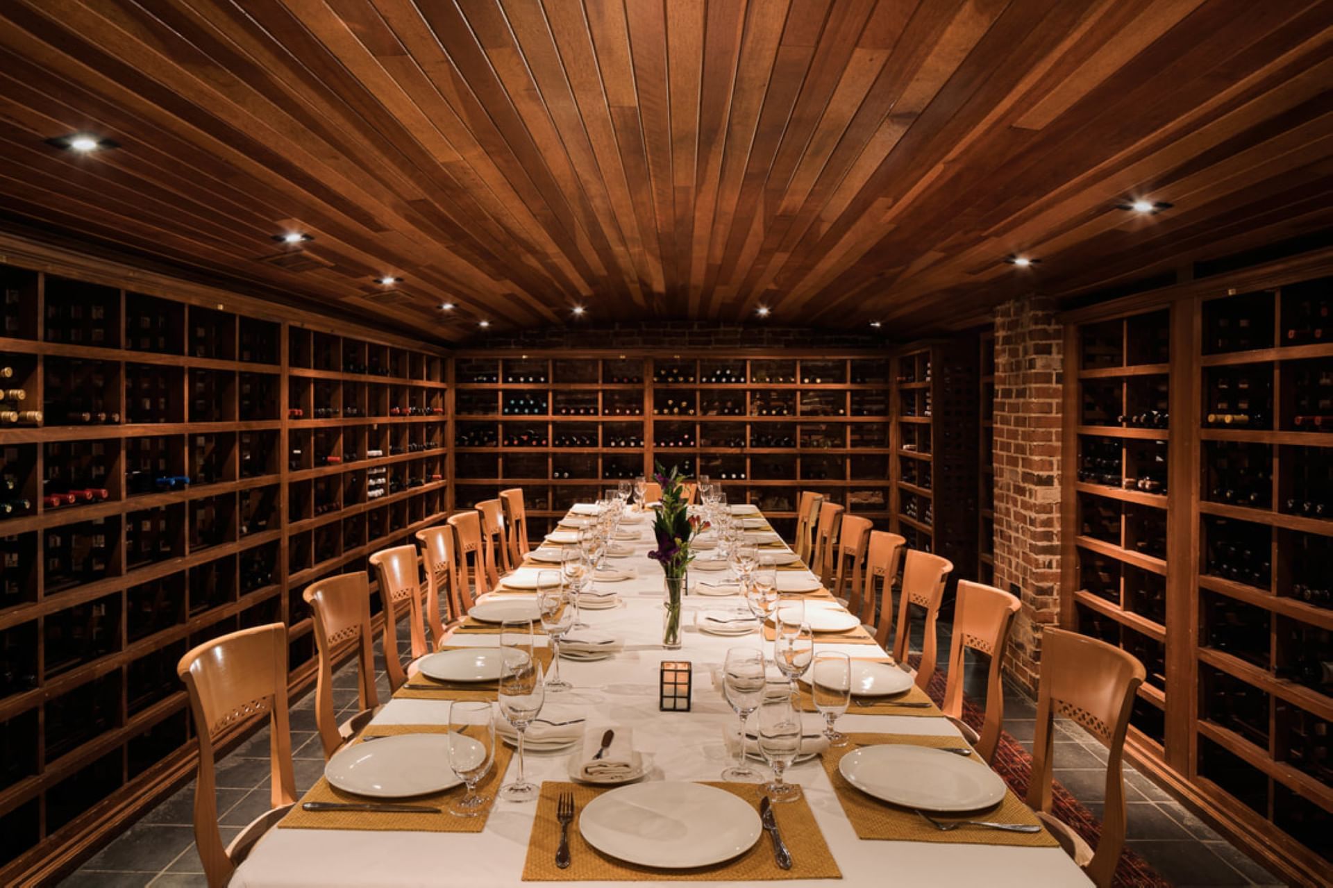 Dining table in Wine Cellar arranged with glassware & cutlery, surrounded by bar shelves at The Clifton