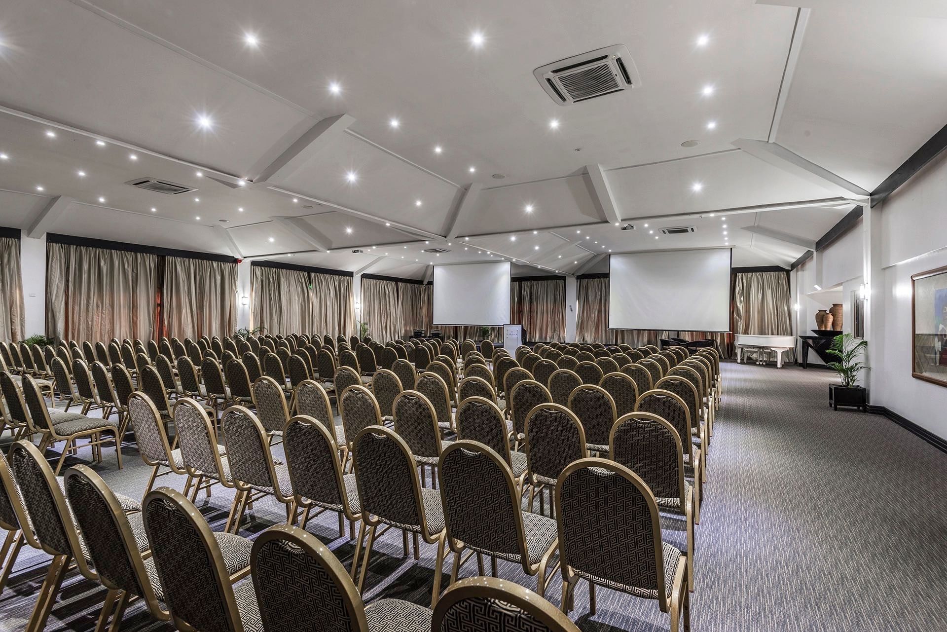 Rows of upholstered chairs by projection screens in Talanoa Hall at Warwick Fiji Resort and Spa