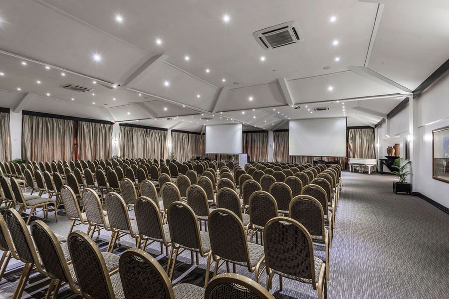 Rows of upholstered chairs by projection screens in Talanoa Hall at Warwick Fiji Resort and Spa