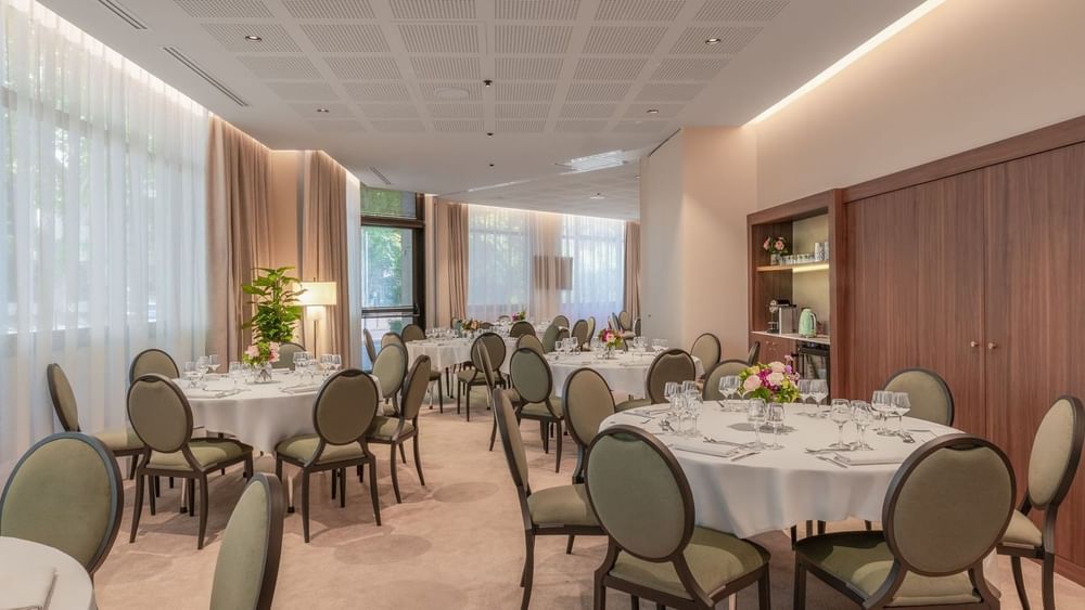 Elegantly arranged event room with round tables and floral centerpieces at Warwick Reine Astrid Lyon.