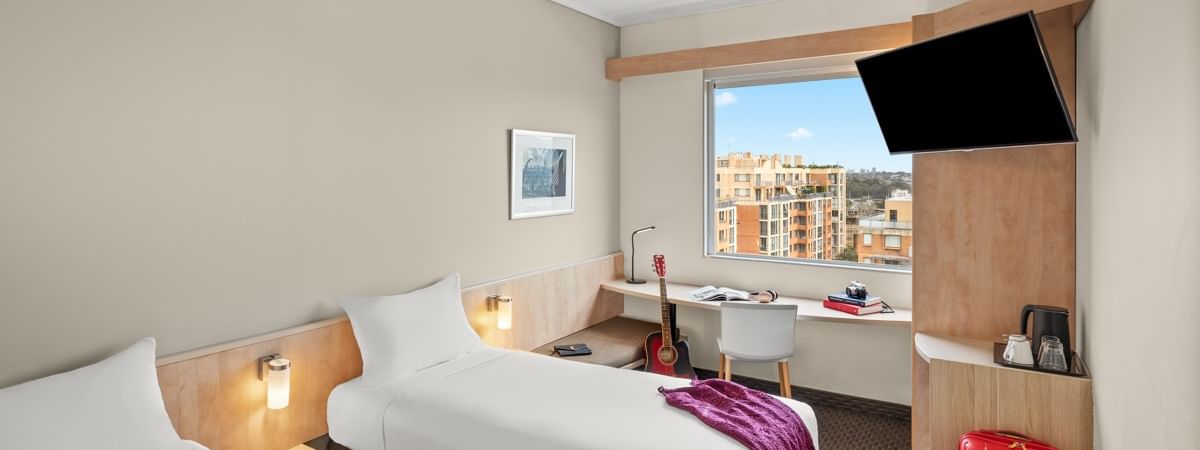 Standard room with two single beds, work desk, wall-mounted TV, and city view at Ibis Sydney Darling Harbour, Pyrmont