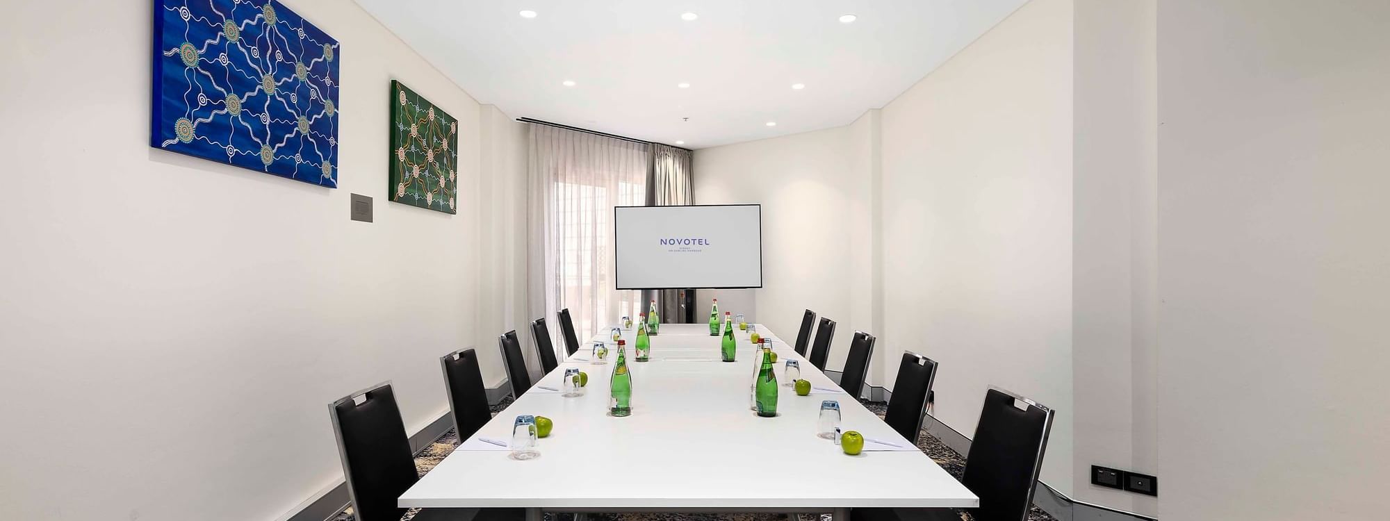 Boardroom set-up facing the projector screen in The Hastings Boardroom at Novotel Sydney on Darling Harbour