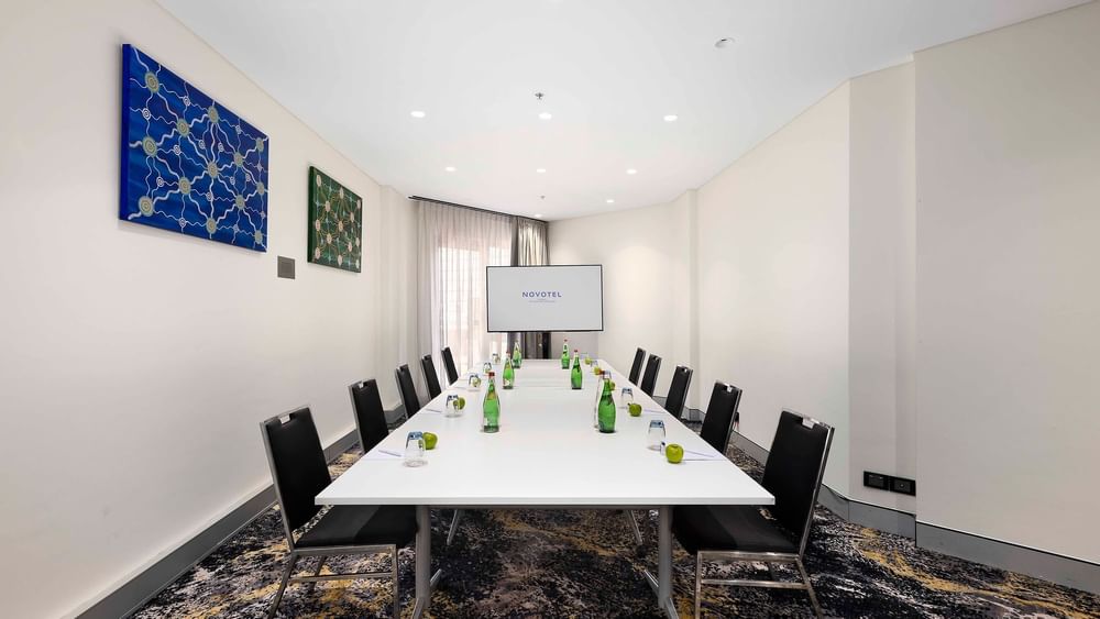 Boardroom set-up facing the projector screen in The Hastings Boardroom at Novotel Sydney on Darling Harbour