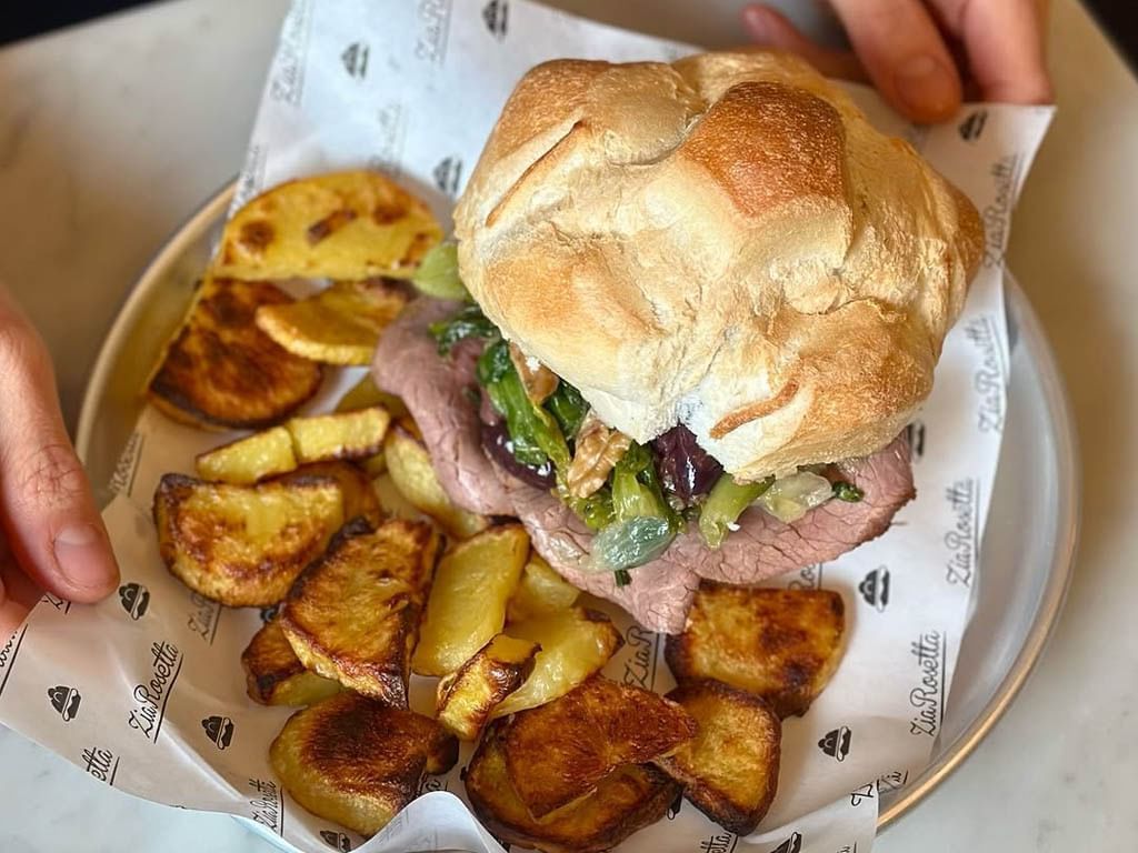 Hearty sandwich filled with roast beef and greens, served with crispy roasted potato wedges in Zia Rosetta at The Glam Hotel