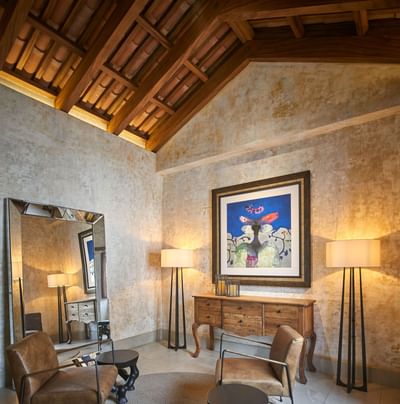 Warm-toned seating area with a rustic-beamed ceiling and an ornate full-length mirror at Singular Signature Residences