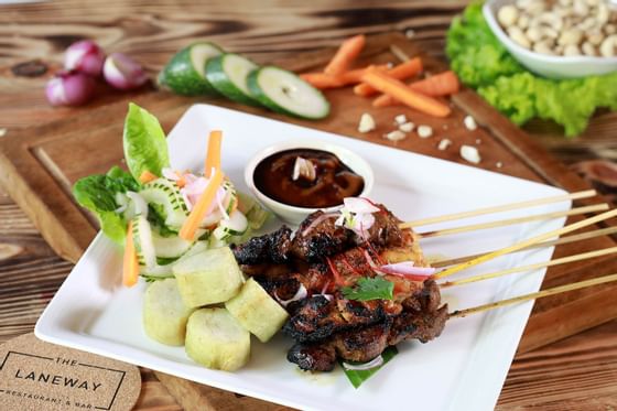 Meat skewers, veggies, and sauce on a plate from The Laneway Restaurant & Bar at Peppers Seminyak
