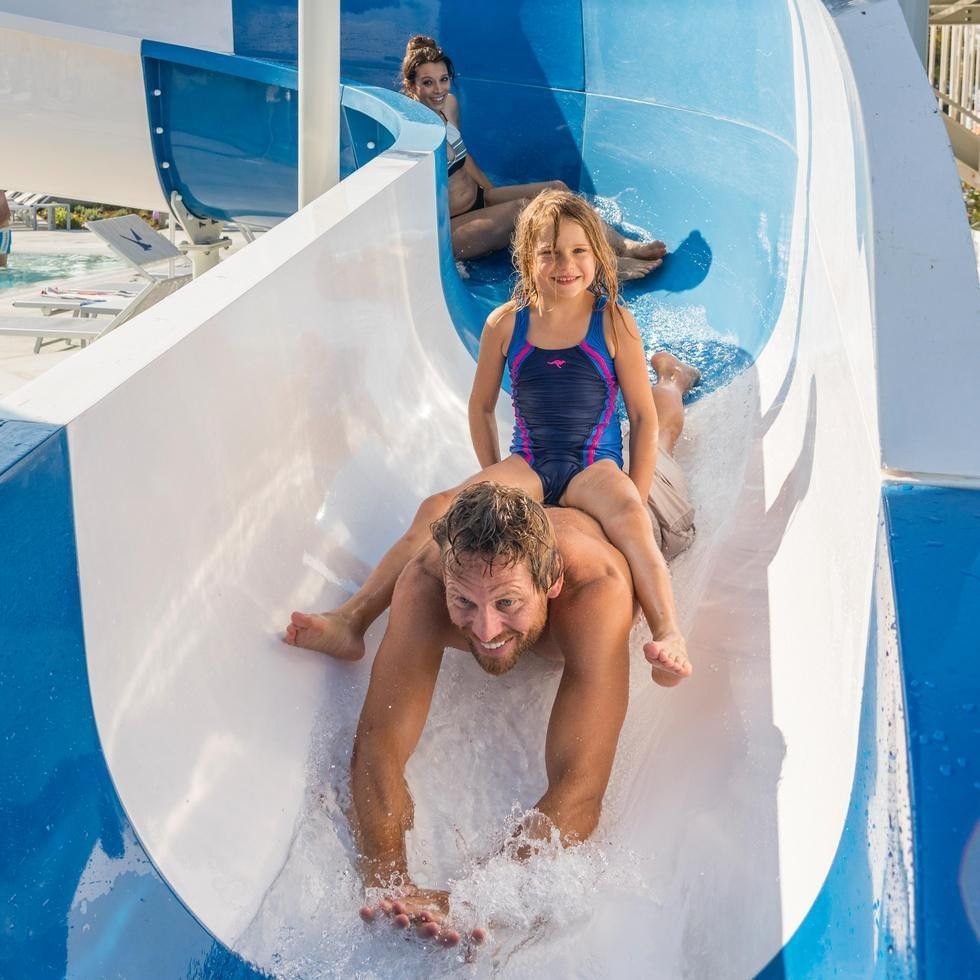 A man and girl slide down a water slide at Falkensteiner Family Resort Sicily