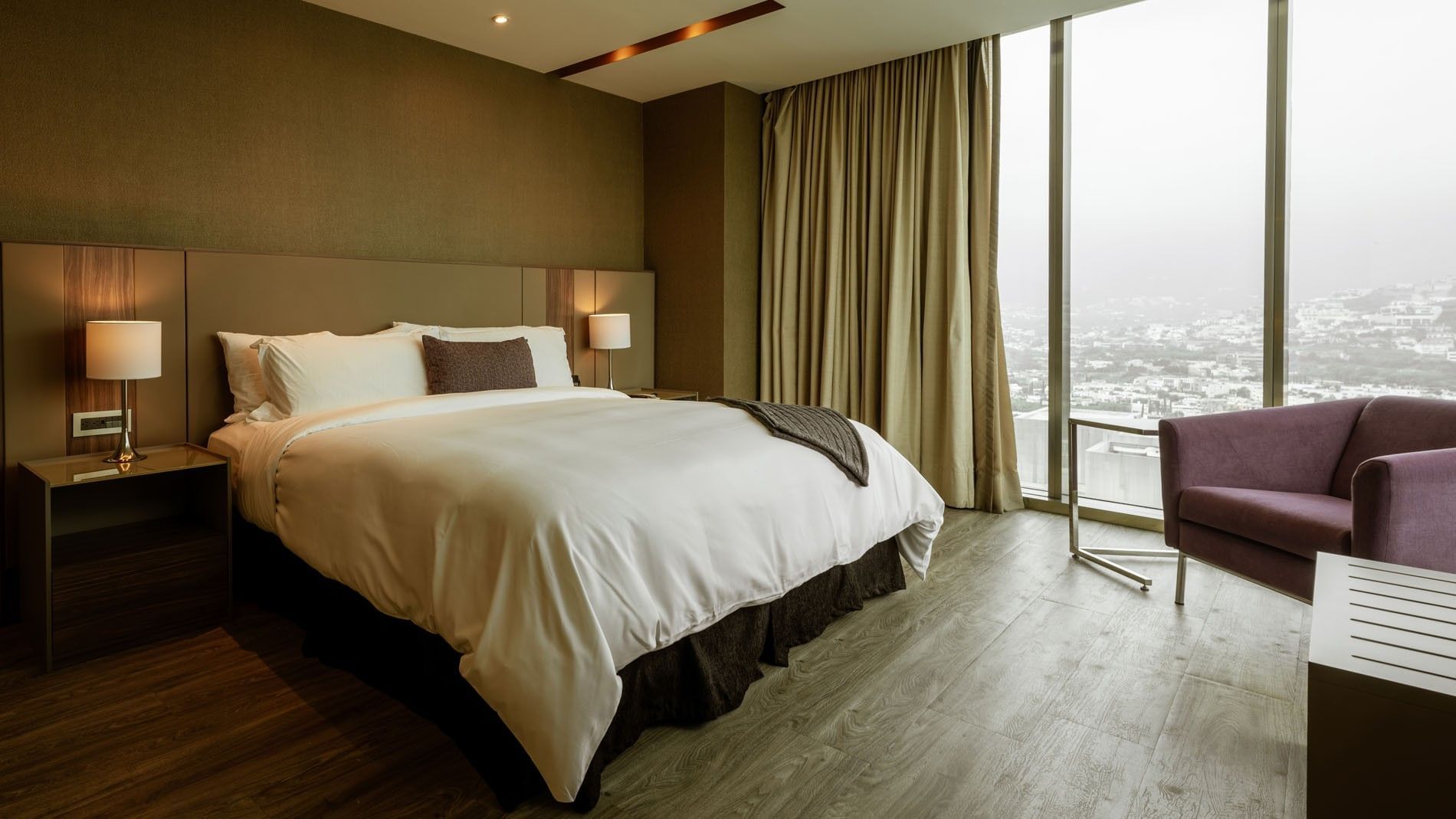 King Junior Suite with a large window overlooking the city view and a purple chair at Camino Real Fashion Drive, Monterrey
