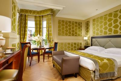 King bed, comfy sofa, work desk & coffee table with fresh flowers in Deluxe King Room at Grand Visconti Palace